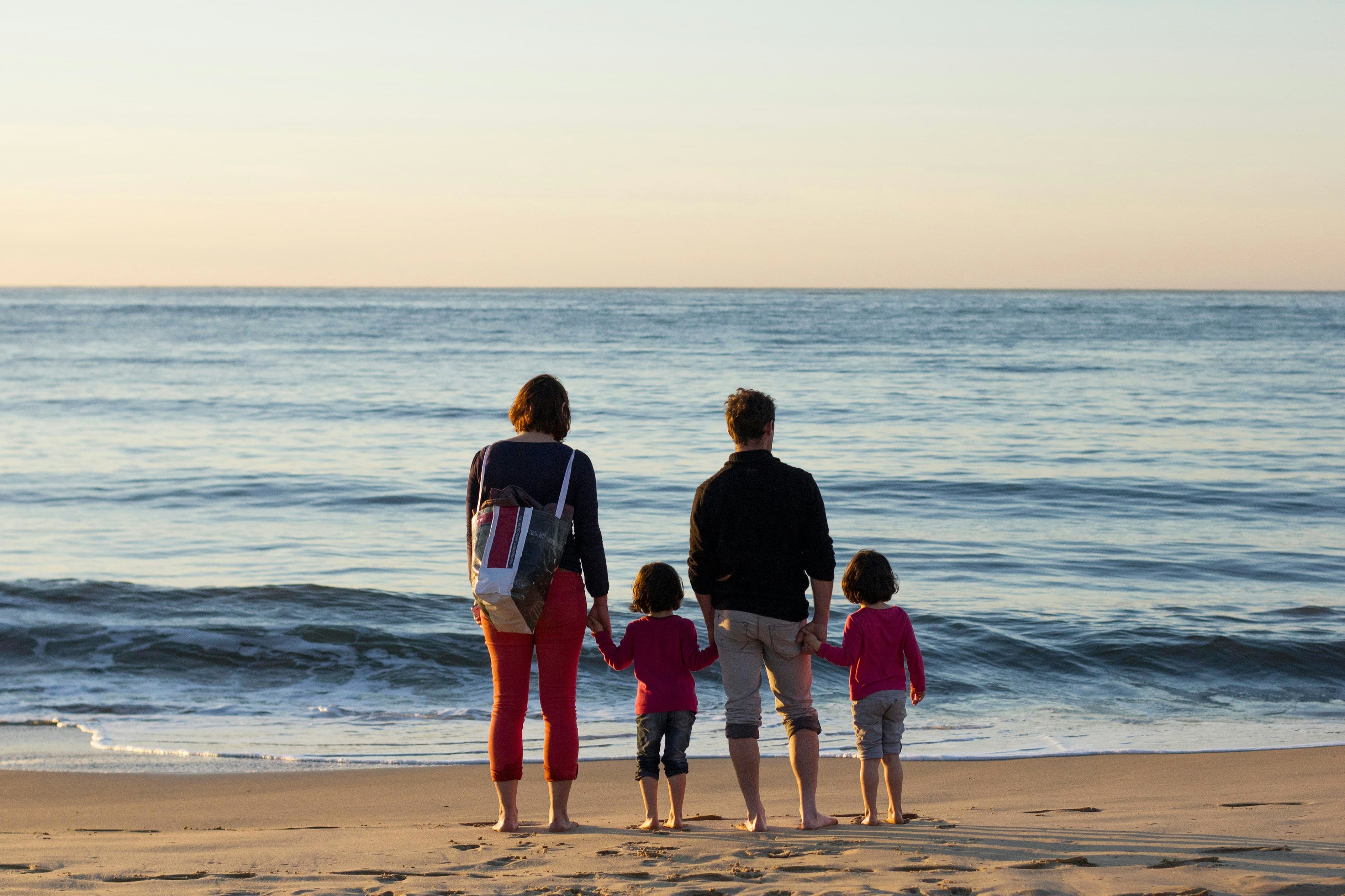 Family holding hands and looking out over the ocean from the beach